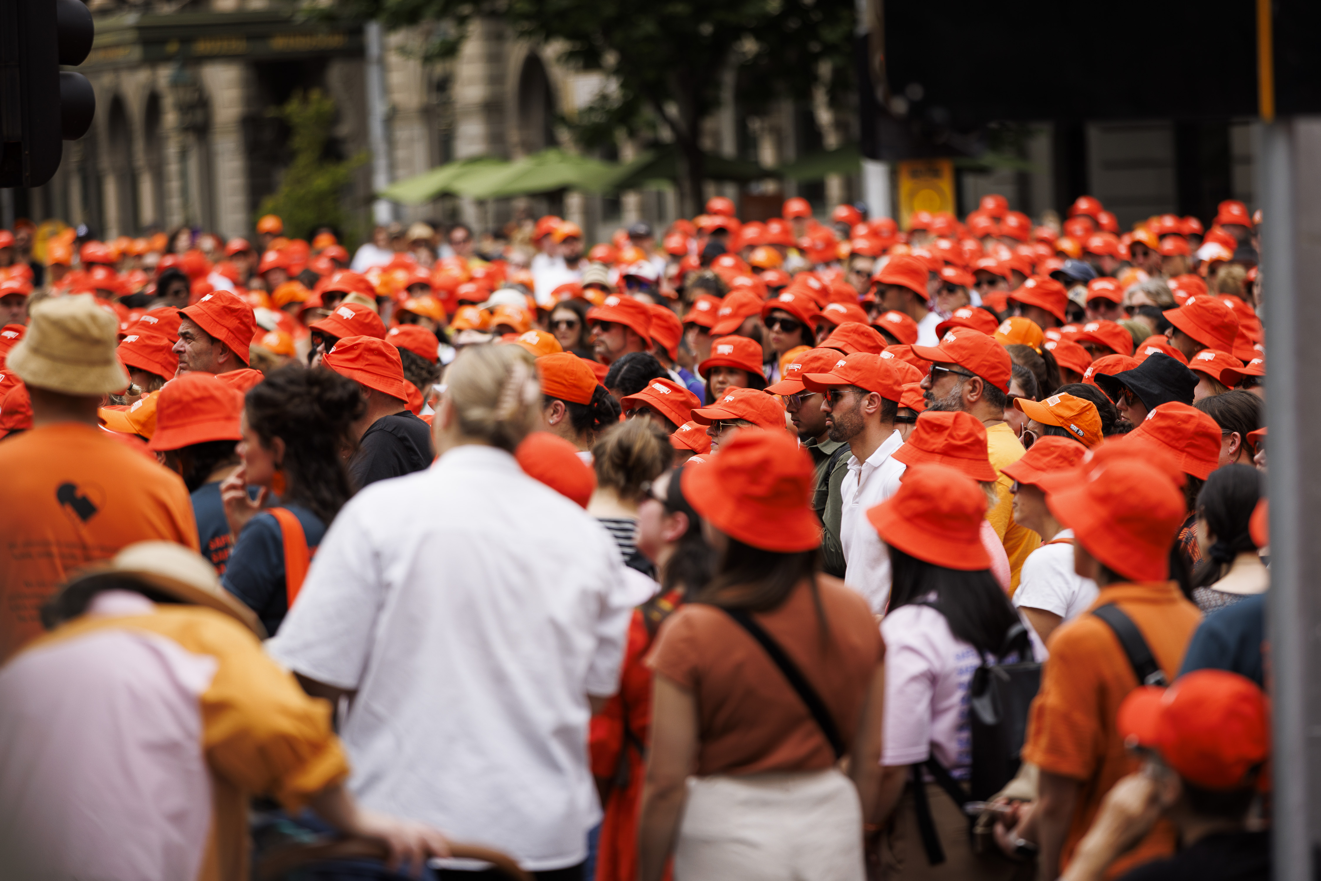 A crowd of people wearing orange Respect Victoria hats gather at the 2023 Walk Against Family Violence. 