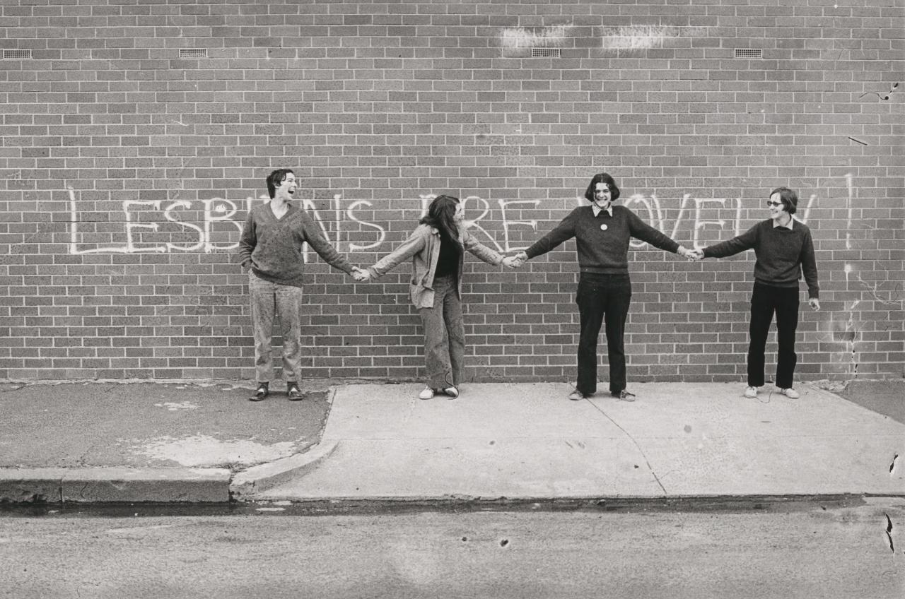 Women holding hands in front of graffiti, Lesbians are lovely